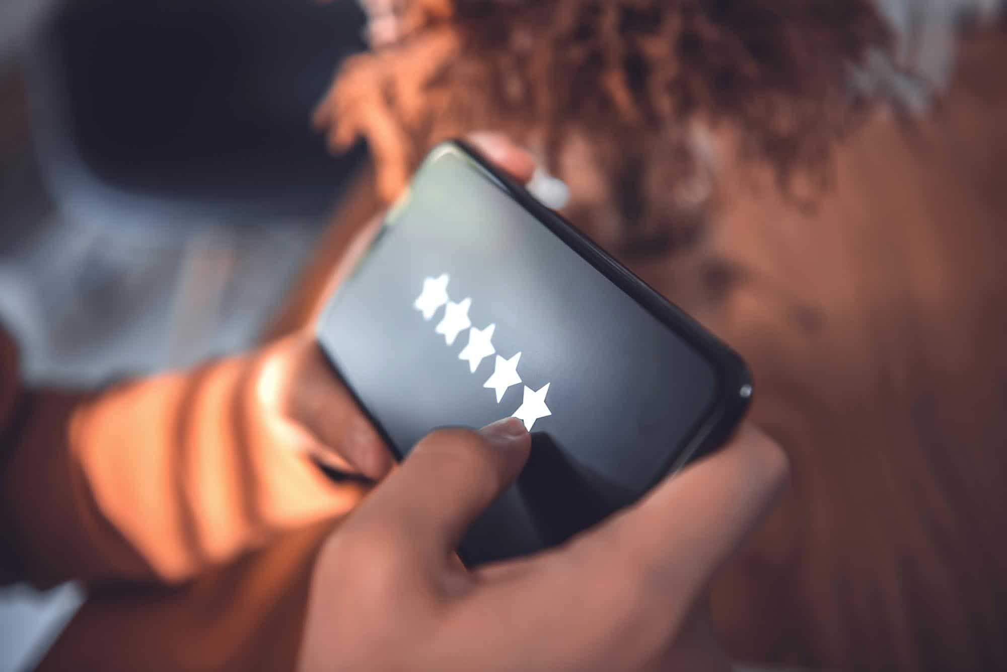 A women's hands hold mobile phones leaving a hotel a 5-star review enhancing the hotels reputation