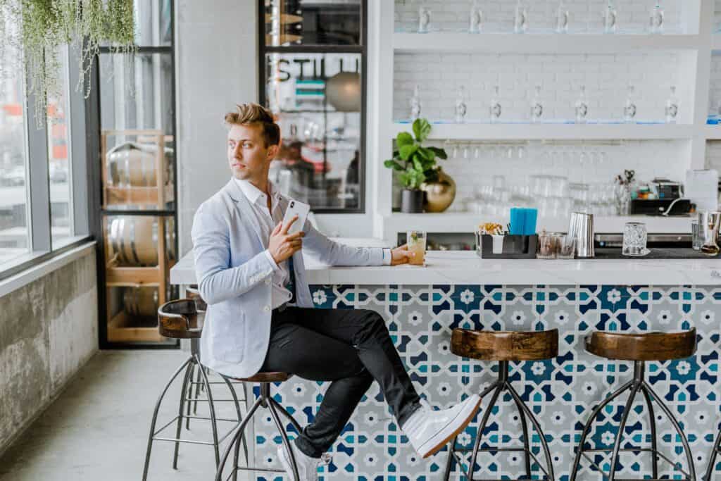 A young man at a cafe is able to use his smartphone to reconfirm his check-in details during the journey to his hotel.