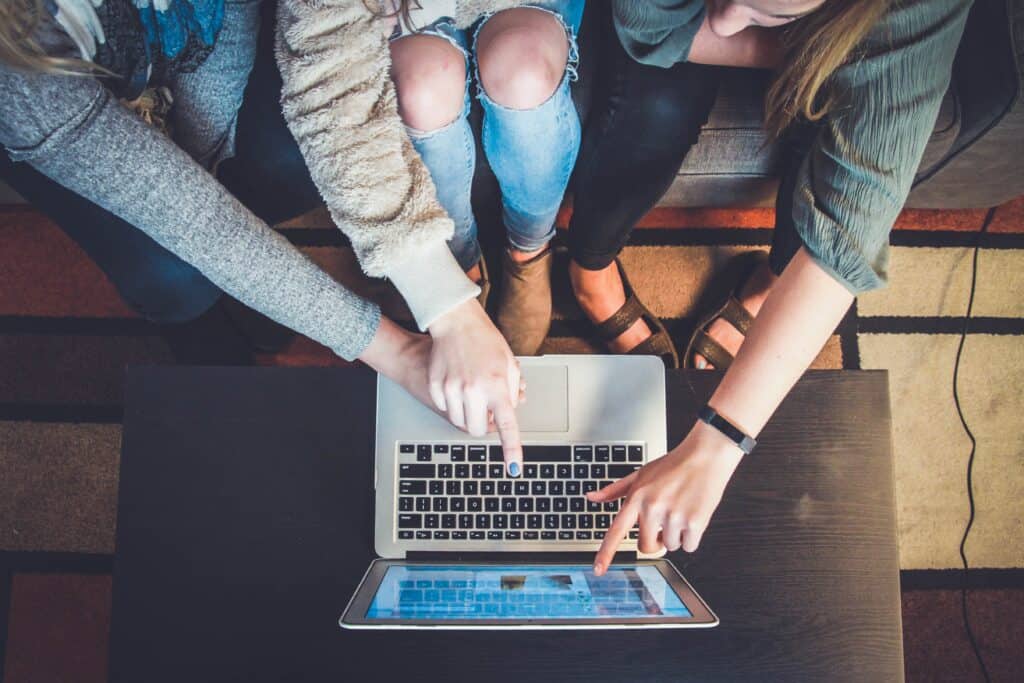 Three women using a laptop to search for the best hotel for their upcoming vacation.