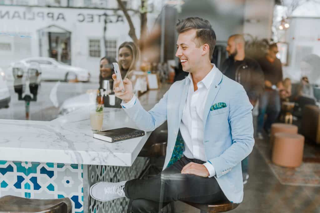 A smiling guest uses their phone to read a new message from the hotel where they’re spending an upcoming stay.